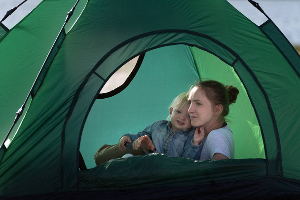 Mutter und Baby im großen Touristenzelt. Zelten mit Kindern. - Foto, Bild
