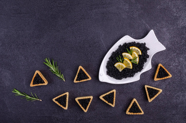 Tartaletas con caviar negro sobre fondo negro. Vista superior. Enfoque selectivo. - Foto, Imagen