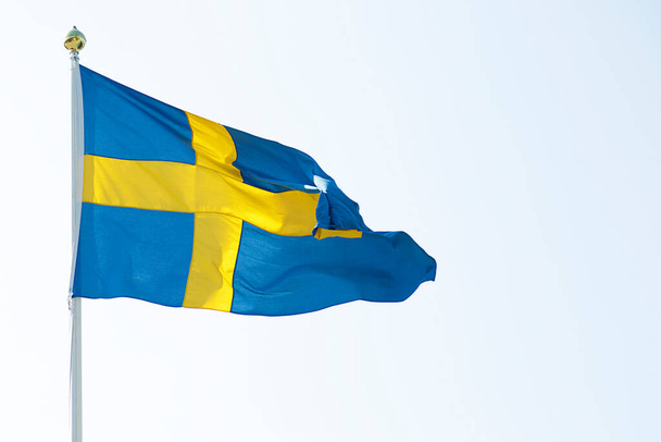 Schwedens Nationalflagge weht im Wind gegen den blauen Himmel  - Foto, Bild