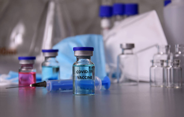Ampullit COVID-19 rokote laboratorion taustakuvissa. Covid 19 rokote ruiskulla ja lasisilla laboratoriolaitteilla kuvia. Laboratoriotarvikkeet varastossa kuva - Valokuva, kuva