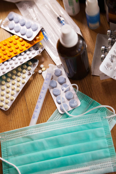 Diverse geneesmiddelen met annotaties, spuiten en medische maskers op tafel - Foto, afbeelding
