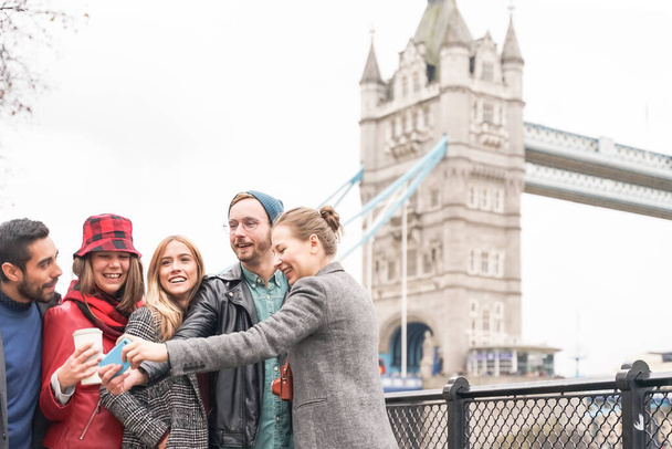 Happy group making a selfies near of Tower Bridge. University students travelling all over the world - Photo, Image