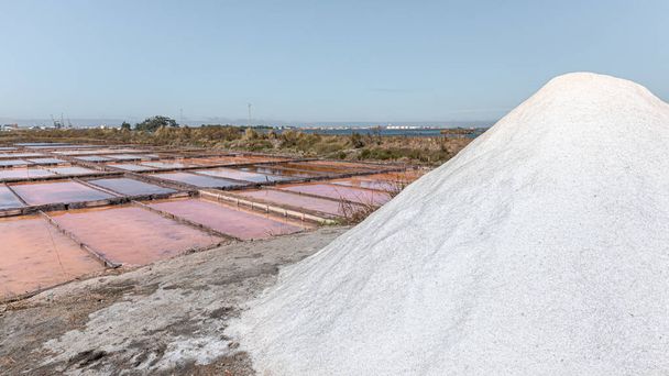 Чудовий краєвид солончаків у Португалії з солоною горою на передньому плані і рожевим кольором, що відбивається у воді. - Фото, зображення