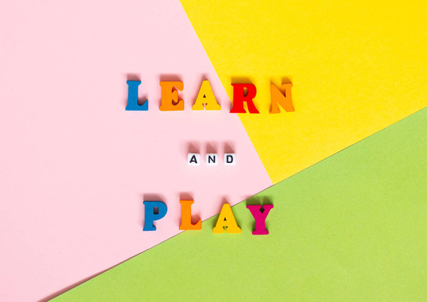 Words made of multi-colored wooden letters "learn and play" on a multi-colored background. Top view. Teaching children - Photo, Image