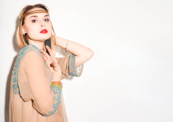 Hippie girl, woman in boho dress, headband, bracelets and earrings. Hippie style, hipster girl. Reggae party. Photo beautiful blonde with red lips on a white background - Φωτογραφία, εικόνα