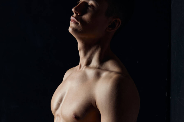 retrato de un atleta con un torso desnudo sobre un fondo negro vista lateral Copiar espacio - Foto, Imagen