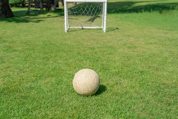 Μπάλα ποδοσφαίρου στο γρασίδι μπροστά από το τέρμα μετά. Ποδόσφαιρο μπάλα στο πράσινο γρασίδι της παιδικής χαράς. - Φωτογραφία, εικόνα