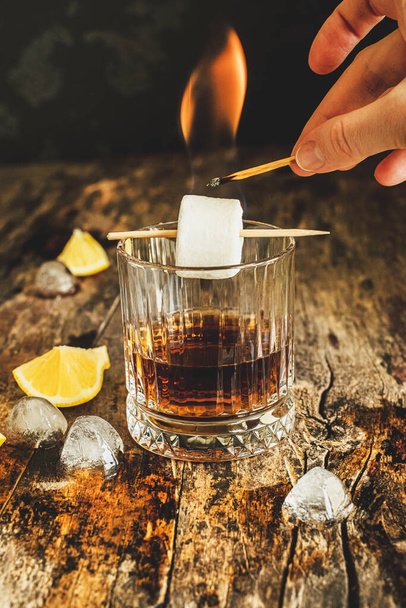 Το χέρι φωτίζει ζαχαρωτά σε ένα ποτήρι κοκτέιλ. Υψηλής ποιότητας φωτογραφία - Φωτογραφία, εικόνα