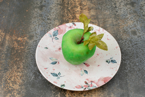 Uma maçã descascada com folhas em belo prato no fundo de mármore. Foto de alta qualidade - Foto, Imagem