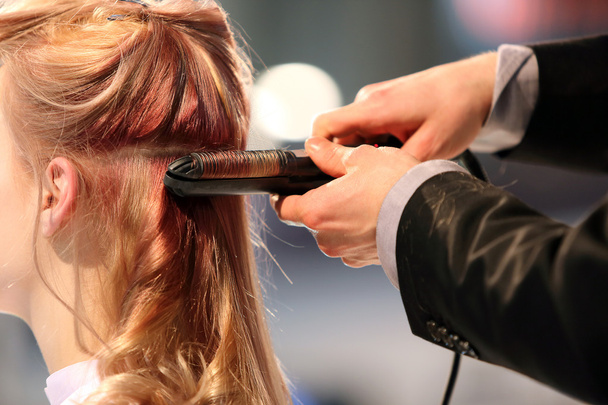 Hairdresser turns hair curling iron of young girl - Φωτογραφία, εικόνα