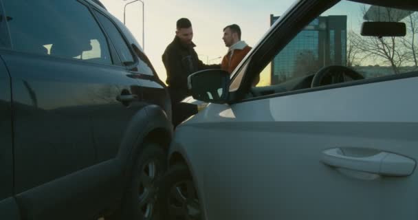 Dos personas discutiendo e inspeccionando el daño después del accidente automovilístico - Imágenes, Vídeo