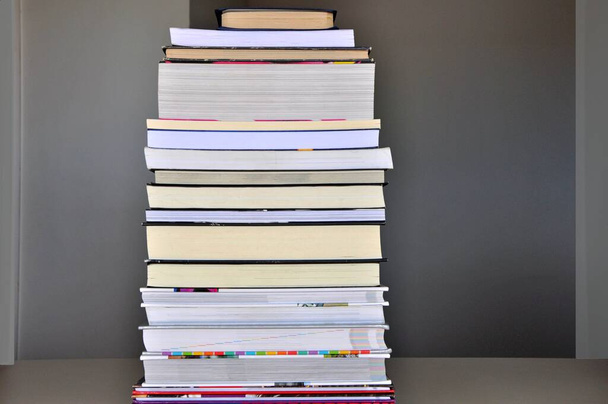 Livres, pile de livres sur une table formant une pyramide de connaissances, livres de différents styles et couleurs. - Photo, image