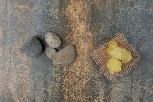 Four rocks with slices of sweet yellow sugar on marble background. High quality photo - Photo, Image