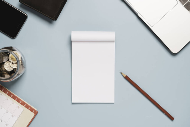 Κάτοψη του λευκού λευκού λευκού χαρτιού με κόκκινο μολύβι laptop και χρήματα σε μπλε φόντο πίνακα. - Φωτογραφία, εικόνα