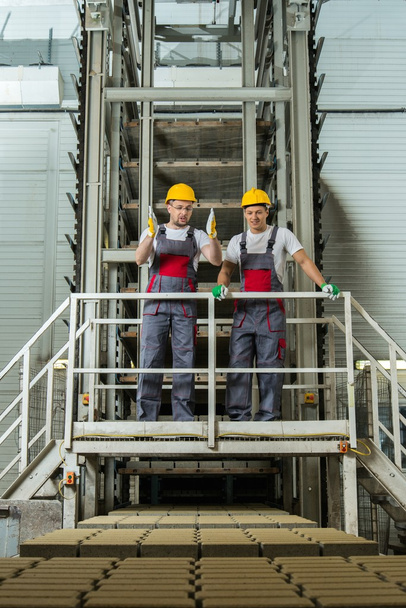 Two men in safety hats on  factory - Valokuva, kuva