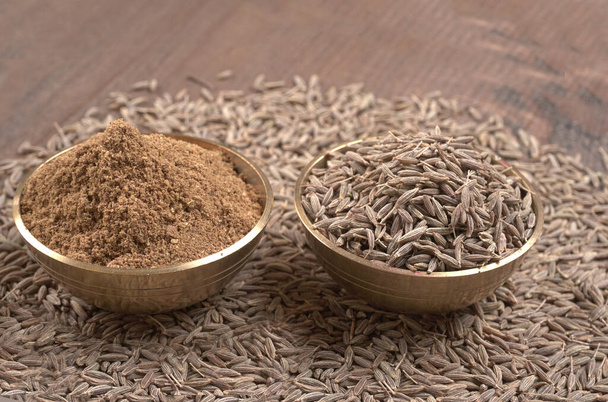 Ground cumin in a bowl and whole cumin, Jeera, on the wooden background. selective focus. - Photo, Image
