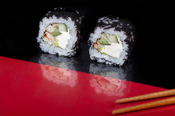 Sushi szett Uramaki, Kalifornia, Philadelphia, egy fehér tányéron. Ünnepi újévi koncepció. Sötét fényvisszaverő háttérrel. Fénymásolási hely. - Fotó, kép