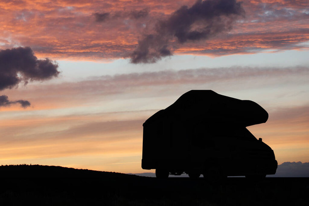 Kempingező szabadidős járművek naplementekor. Kempingezés a természetben. Nyaralás és utazás lakókocsiban otthon. - Fotó, kép
