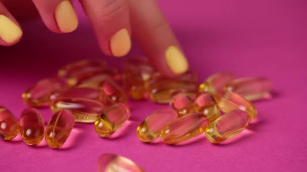 A nő megérinti a kapszulákat az ujjaival. Sárga omega 3 tabletta. - Felvétel, videó