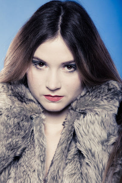 Portrait of girl with long hair. Young woman in fur coat on blue. - Photo, Image