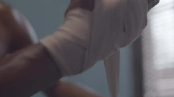 Close-up tiro de mãos de boxeador masculino afro-americano irreconhecível com peito nu envolvendo tiras de boxe em torno de seu pulso antes de treinar - Filmagem, Vídeo