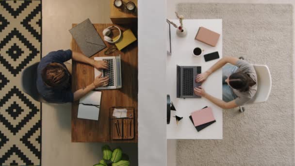 Top view shot młodych mężczyzn i kobiet siedzących w różnych pomieszczeniach oddzielonych ścianą i pracujących na swoich laptopach - Materiał filmowy, wideo