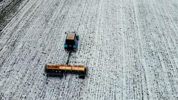 Amplia y cercana variedad de tomas que muestran tierra fertilizante y se preparan para la primavera usando tractor que trabaja en campo agronómico con capa de nieve en invierno - Imágenes, Vídeo