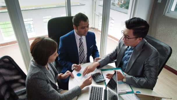 High Angle Pohled na dva podnikatele a jejich kolegyni sedící u pracovního stolu a hovořící o schématech z dokumentů ležících na stole - Záběry, video