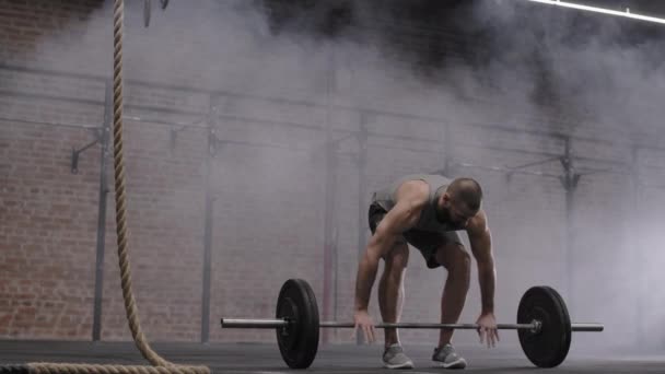 Große Aufnahme eines gut aussehenden kaukasischen Sportlers in Sportkleidung, der eine schwere Langhantel in der Turnhalle hochhebt und Muskeln an Beinen und Gesäß pumpt - Filmmaterial, Video
