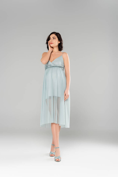 Stylish pregnant woman standing on grey background - Valokuva, kuva