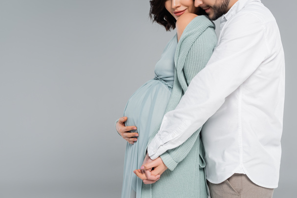 Vista ritagliata dell'uomo che abbraccia moglie incinta isolata su grigio  - Foto, immagini