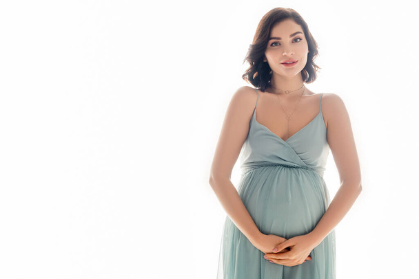 Zwangere vrouw glimlachen op camera geïsoleerd op wit - Foto, afbeelding