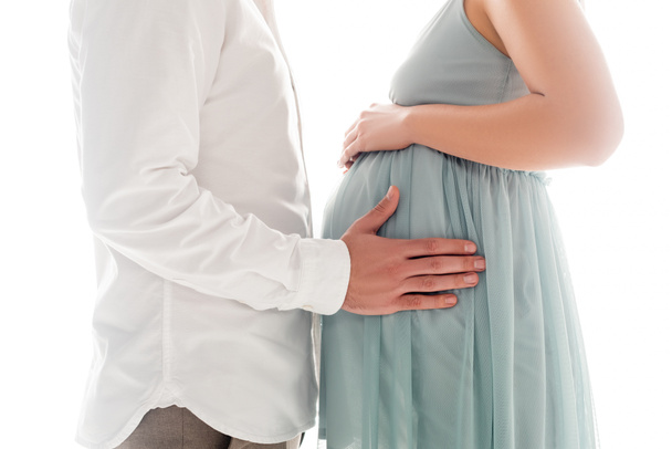 Recortado vista de hombre en blanco shier tocando vientre de embarazada esposa aislado en blanco - Foto, imagen