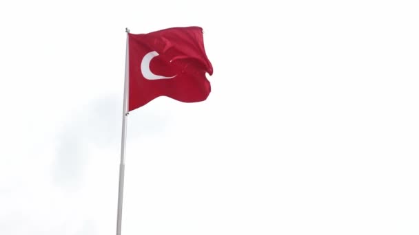 Red Turkish flag in a windy weather. White sky in background. Popular tourist destination for sea vacation in all inclusive hotel. Patriotic symbol of Turkey. Flag on a pole trembling because of wind. - Πλάνα, βίντεο