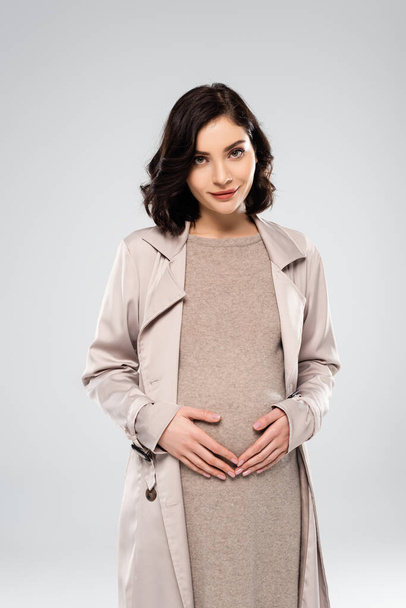 Pregnant woman in coat looking at camera isolated on grey  - Photo, Image