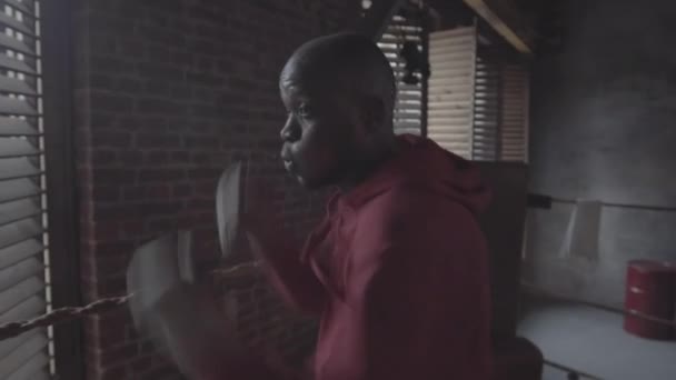 Vyötärö-up laukaus 20-jotain Afrikkalainen amerikkalainen taistelija huppari varjo nyrkkeily ottelukerhossa ja suorittaa jabs, uppercuts ja koukut - Materiaali, video