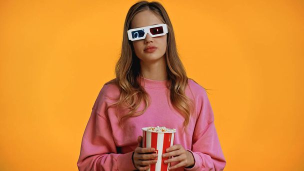 nastolatka dziewczyna w 3d okulary trzymając wiadro z popcornem izolowane na żółto - Zdjęcie, obraz