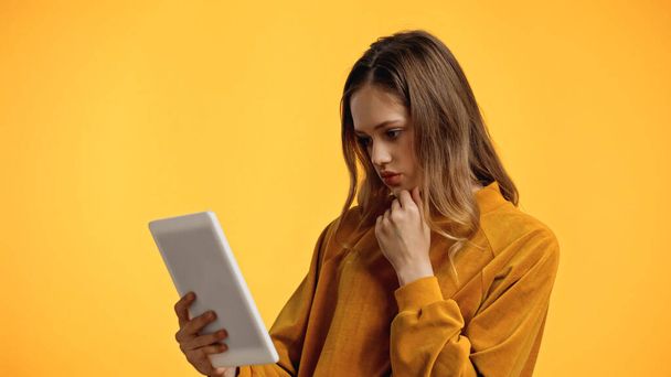 adolescente en suéter mirando tableta digital aislado en amarillo - Foto, Imagen