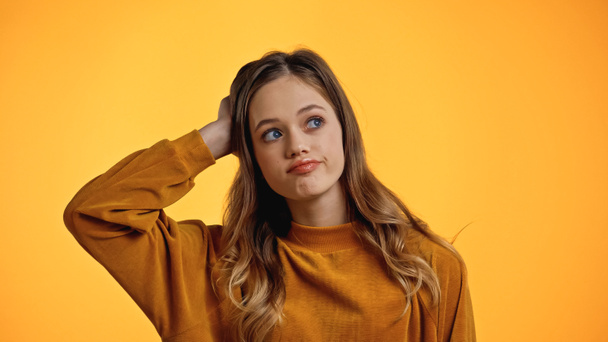 вдумчивая девушка-подросток в свитере смотрит в сторону, изолированную от желтого - Фото, изображение