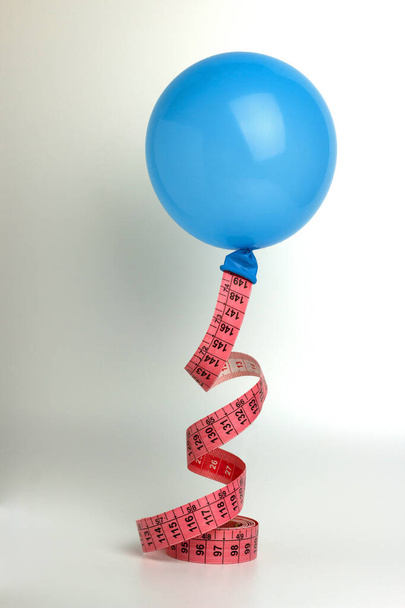 Composição criativa com balão e fita métrica sobre fundo branco. planejamento de perda de peso. Conceito de nutrição saudável. Espaço de cópia. - Foto, Imagem