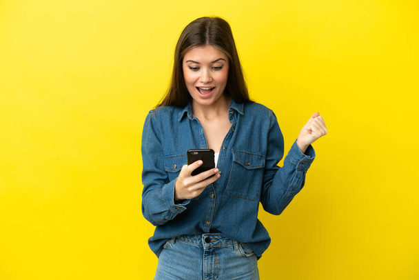 Young caucasian woman isolated on yellow background surprised and sending a message - Foto, Imagem