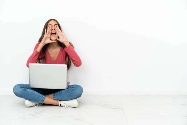 Jeune fille française assise sur le sol avec son ordinateur portable criant et annonçant quelque chose - Photo, image