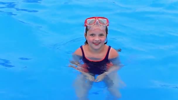 Een kind in een badpak en een watermasker zwemt in het zwembad van het waterpark. - Video