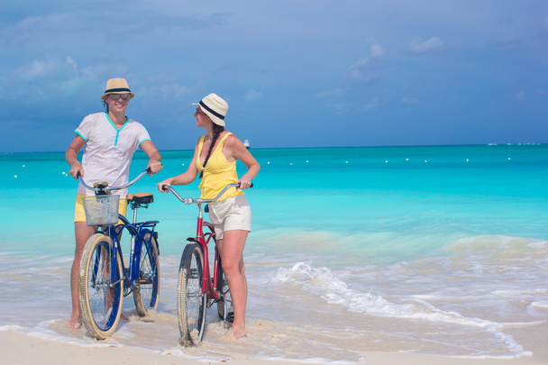Young happy couple riding bikes on white tropical beach - Photo, Image