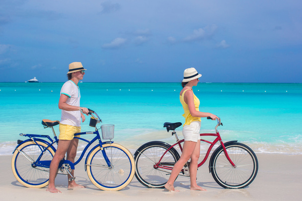 Nuori onnellinen pari ratsastus polkupyörää valkoinen hiekkaranta
 - Valokuva, kuva