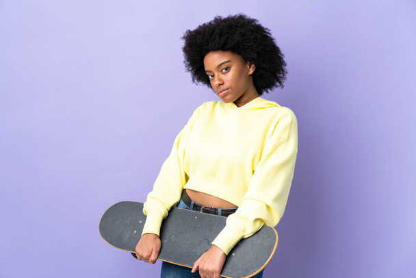 若いアフリカ系アメリカ人の女性はスケートで紫色の背景に隔離された - 写真・画像