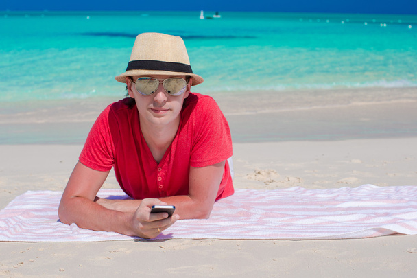 熱帯白いビーチでの携帯電話を持つ若い男 - 写真・画像