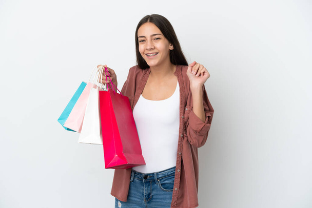 jong frans meisje geïsoleerd op witte achtergrond holding shopping tassen en glimlachen - Foto, afbeelding