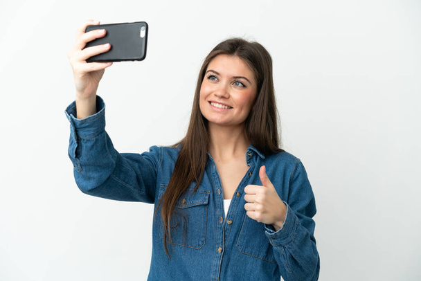 Young caucasian woman isolated on white background making a selfie with mobile phone - Фото, изображение