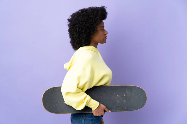 Young African American woman isolated on purple background with a skate - Photo, image
